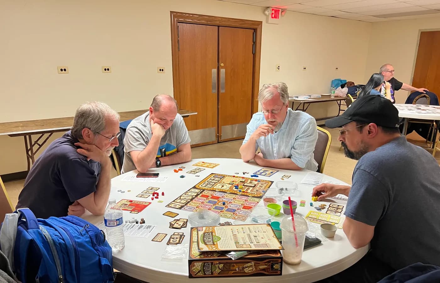 Four people deep in a board game at a round table