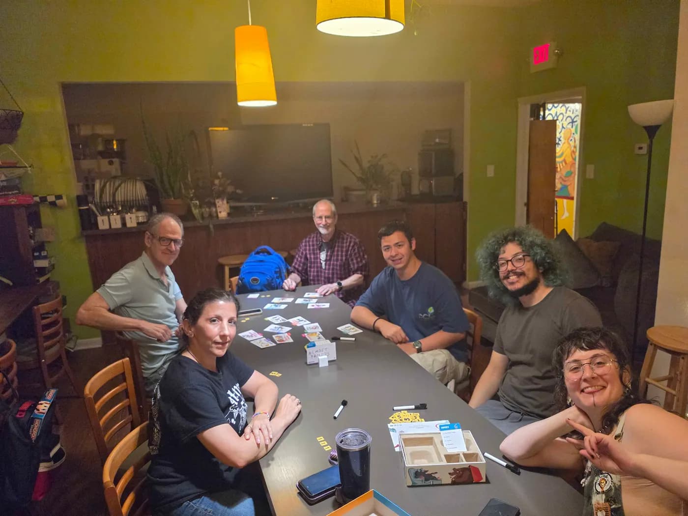 Seven people smiling around a game table